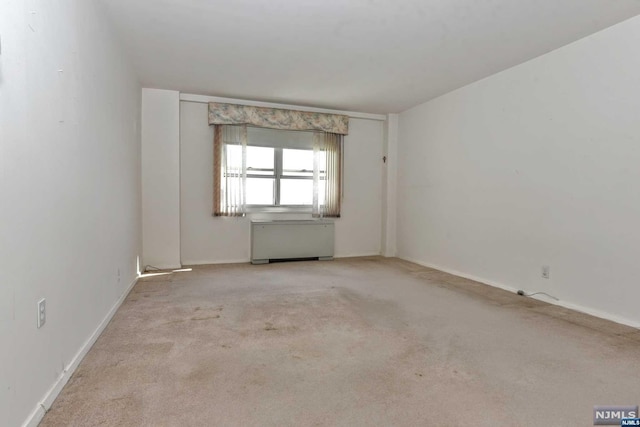 unfurnished room featuring light carpet and radiator