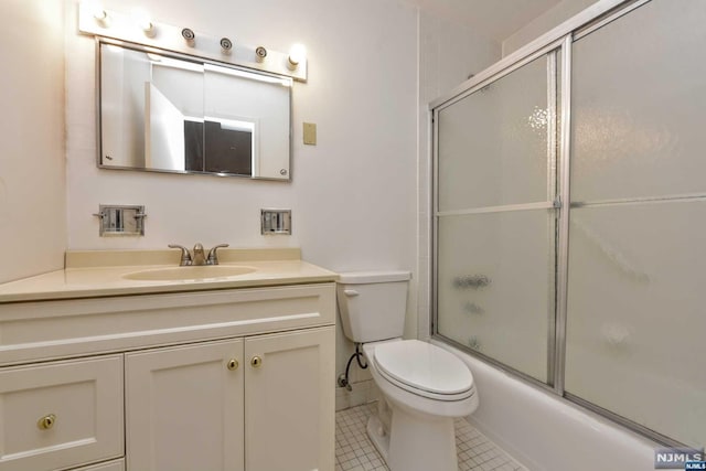 full bathroom featuring combined bath / shower with glass door, vanity, tile patterned floors, and toilet