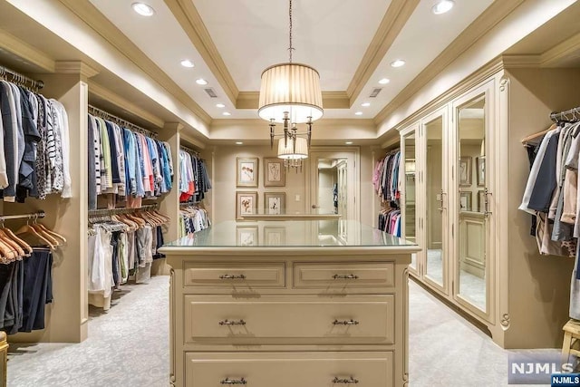 walk in closet with light carpet, a raised ceiling, and a notable chandelier