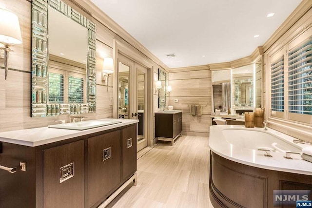 bathroom with wood-type flooring, vanity, a bathtub, and crown molding