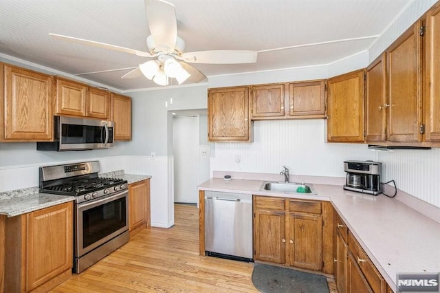 kitchen featuring ceiling fan, sink, light hardwood / wood-style floors, appliances with stainless steel finishes, and ornamental molding