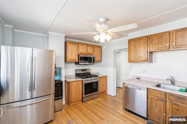 kitchen featuring appliances with stainless steel finishes, ceiling fan, crown molding, sink, and light hardwood / wood-style floors