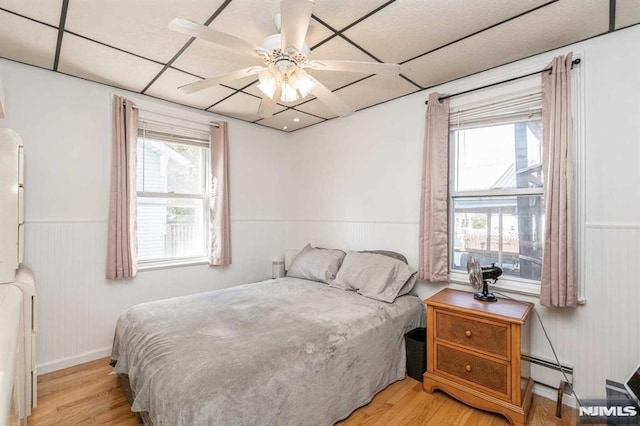 bedroom featuring a paneled ceiling, ceiling fan, light hardwood / wood-style floors, and a baseboard radiator