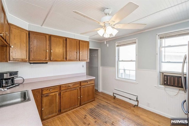 kitchen featuring ceiling fan, crown molding, a baseboard heating unit, sink, and light hardwood / wood-style floors