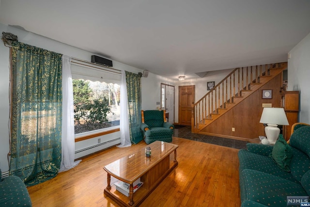 living room featuring hardwood / wood-style flooring, baseboard heating, and wood walls