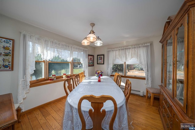 dining space with a baseboard heating unit, a wealth of natural light, and light hardwood / wood-style floors