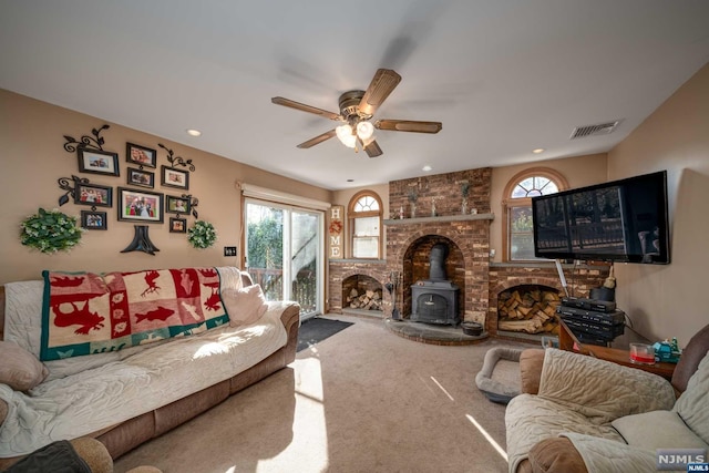 living room with ceiling fan, carpet flooring, and a wood stove