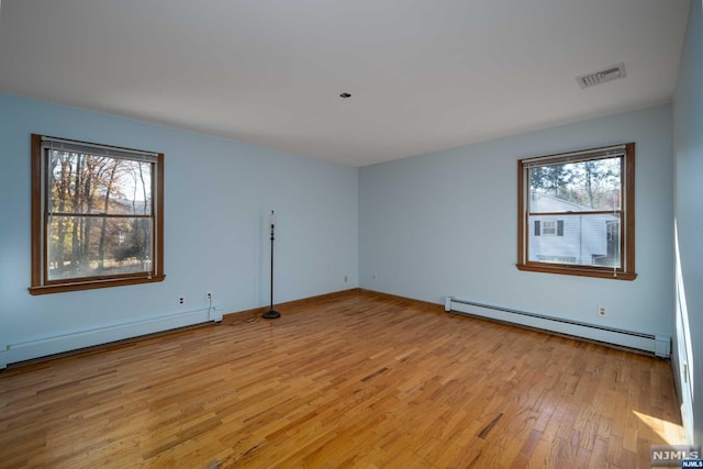 unfurnished room featuring light hardwood / wood-style flooring, a baseboard heating unit, and plenty of natural light