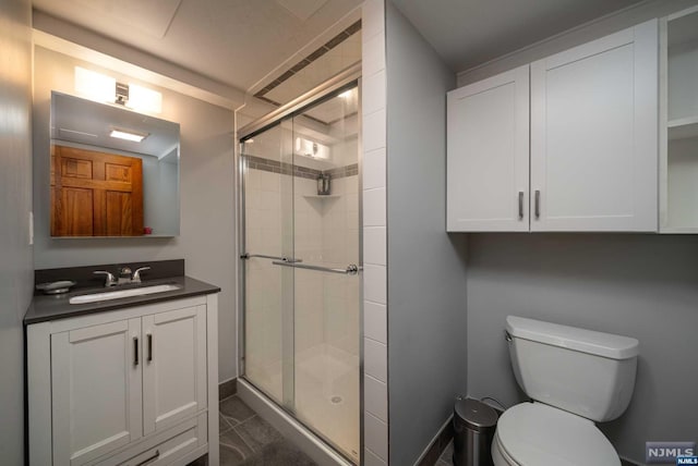 bathroom with vanity, toilet, tile patterned flooring, and a shower with door