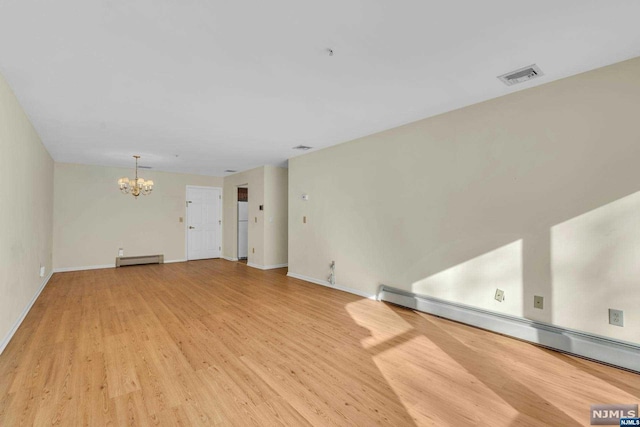 empty room featuring a chandelier, light hardwood / wood-style flooring, and a baseboard heating unit