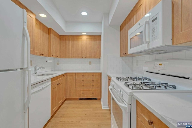 kitchen with sink, light brown cabinets, white appliances, decorative backsplash, and light wood-type flooring