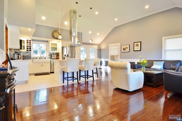 living room with crown molding, sink, high vaulted ceiling, and light wood-type flooring