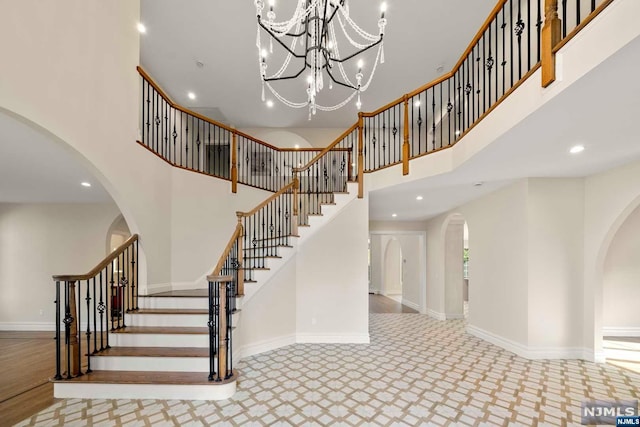 staircase with a towering ceiling and a notable chandelier