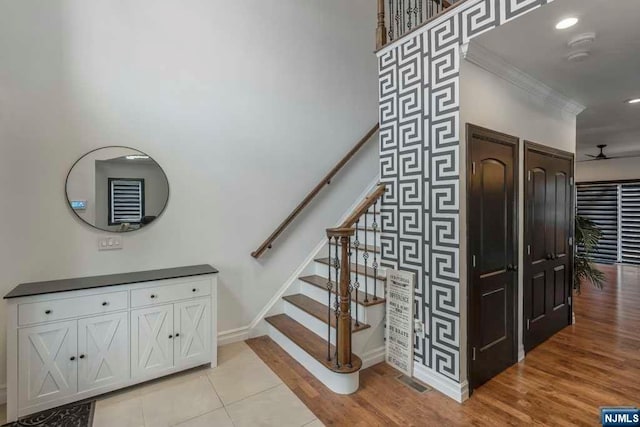 stairs with hardwood / wood-style floors, ceiling fan, and ornamental molding