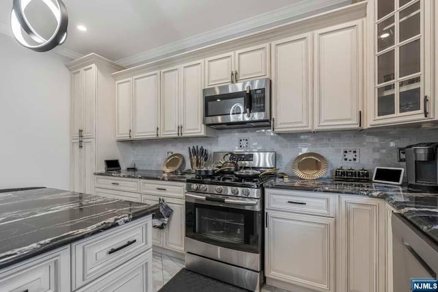 kitchen with appliances with stainless steel finishes, backsplash, ornamental molding, cream cabinets, and dark stone countertops