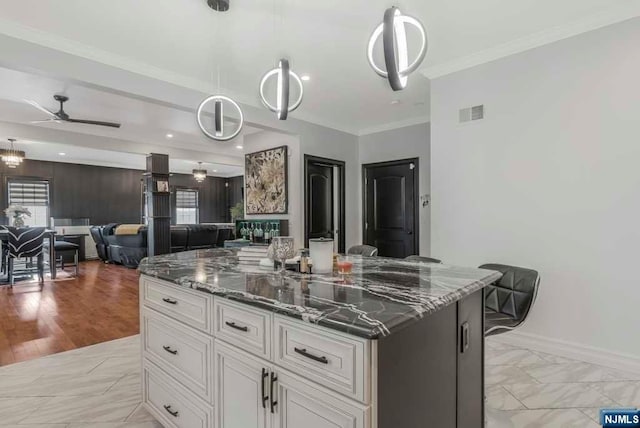 kitchen with white cabinets, ceiling fan, a kitchen island, and pendant lighting