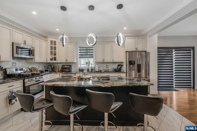 kitchen with appliances with stainless steel finishes, a center island, decorative light fixtures, and dark stone counters