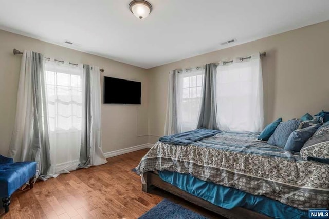 bedroom with multiple windows and hardwood / wood-style flooring