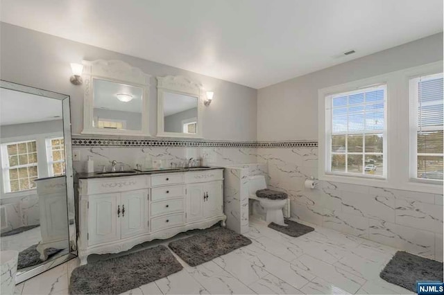 bathroom featuring plenty of natural light, tile walls, and vanity