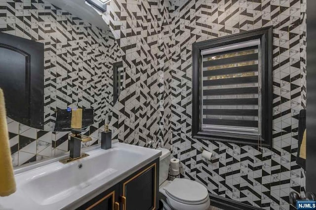 bathroom featuring vanity, toilet, and tile walls