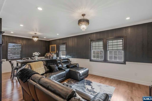 living room with ornamental molding, light wood-type flooring, and an inviting chandelier