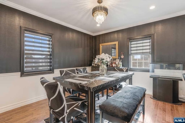 dining space featuring an inviting chandelier, ornamental molding, and light hardwood / wood-style flooring