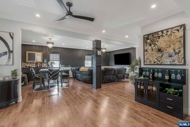 living room with ceiling fan, hardwood / wood-style floors, and wooden walls