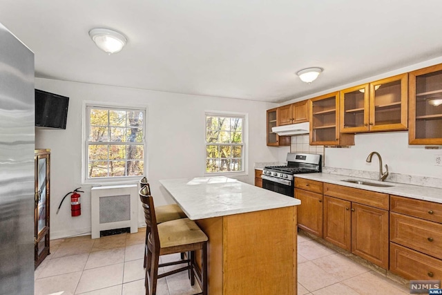 kitchen featuring a center island, sink, gas range, radiator heating unit, and a breakfast bar area