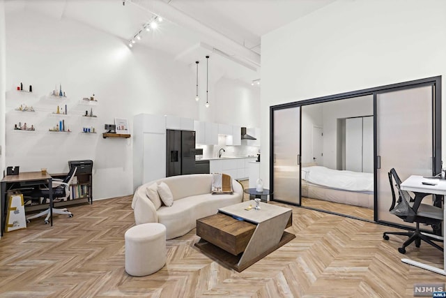 living room with beamed ceiling, light parquet floors, track lighting, and high vaulted ceiling