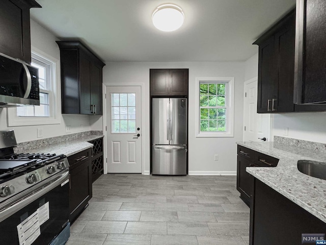 kitchen featuring light stone countertops, appliances with stainless steel finishes, and sink