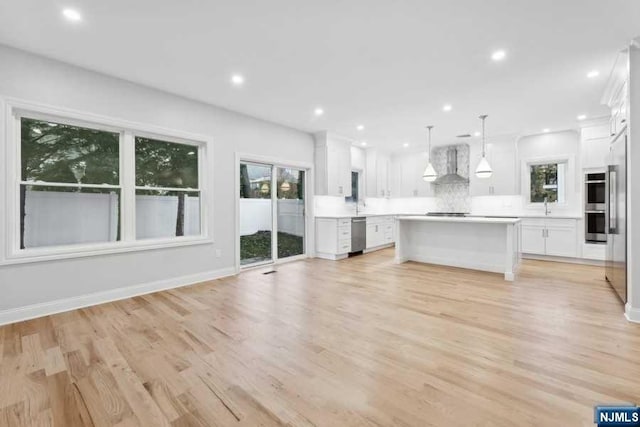 unfurnished living room with sink, plenty of natural light, and light wood-type flooring