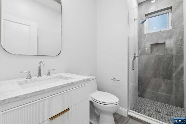 bathroom featuring vanity, a shower with shower door, and toilet