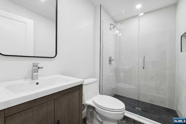 bathroom featuring vanity, a shower with shower door, and toilet