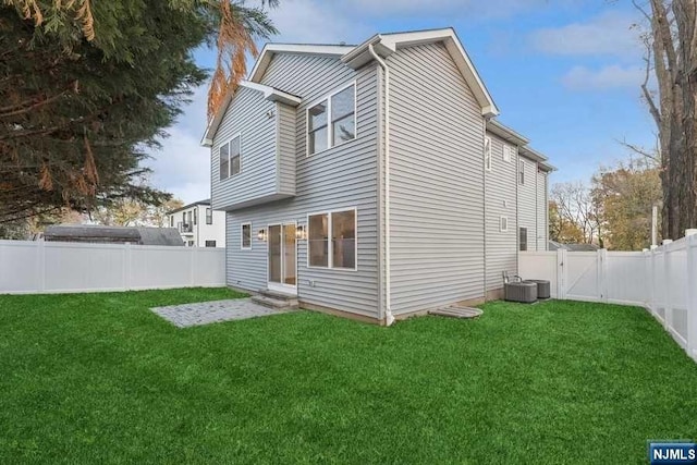 rear view of property featuring a yard and central AC