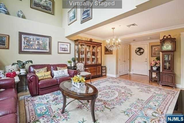 living room featuring crown molding, light wood-type flooring, and a notable chandelier