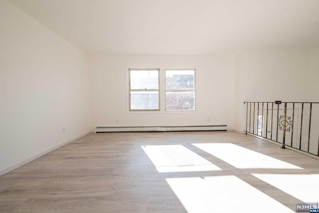 spare room with light hardwood / wood-style floors and a baseboard heating unit