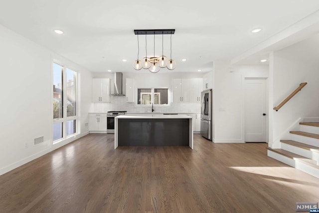 kitchen featuring dark hardwood / wood-style flooring, stainless steel appliances, decorative light fixtures, a center island, and white cabinetry