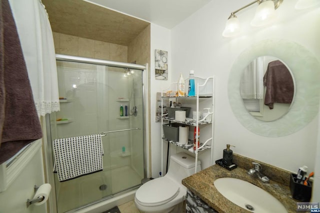 bathroom featuring toilet, an enclosed shower, and vanity