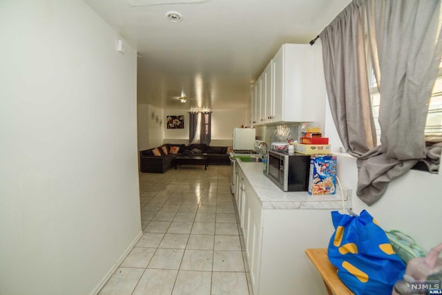 kitchen with white cabinets, light tile patterned flooring, and sink