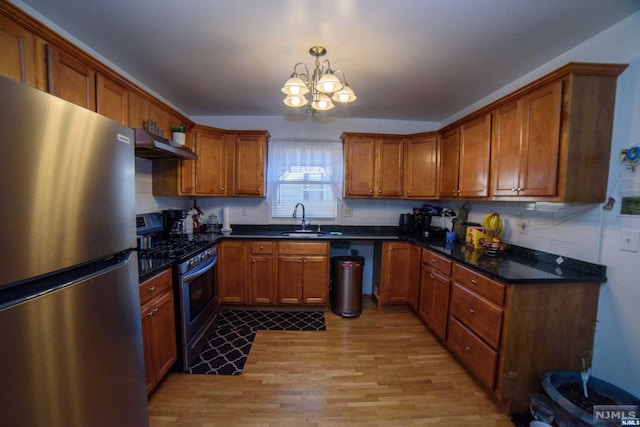 kitchen featuring pendant lighting, sink, light wood-type flooring, range hood, and appliances with stainless steel finishes