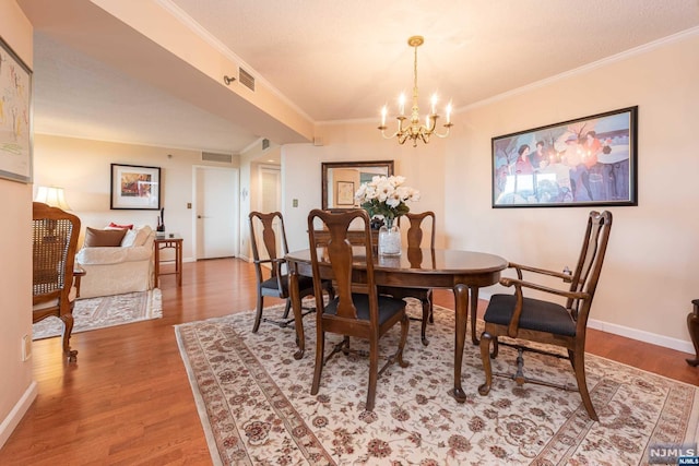 dining room featuring an inviting chandelier, ornamental molding, a textured ceiling, and hardwood / wood-style flooring