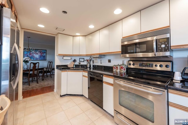 kitchen with a chandelier, white cabinets, light wood-type flooring, and appliances with stainless steel finishes