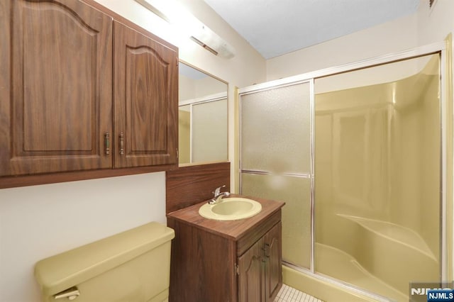 bathroom with vanity, toilet, and a shower with shower door