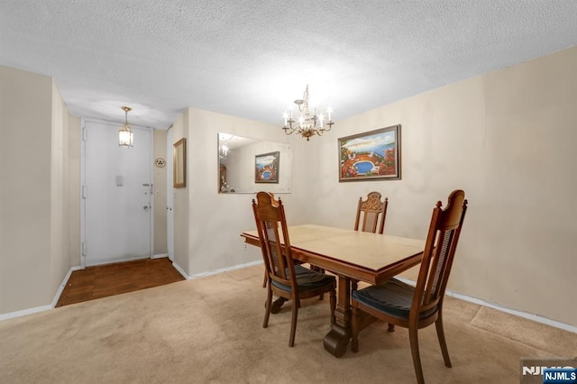 carpeted dining space featuring a notable chandelier and a textured ceiling