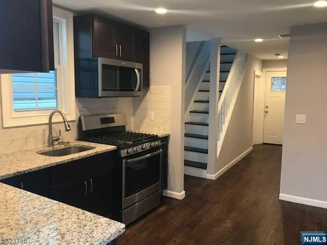 kitchen featuring light stone countertops, sink, dark hardwood / wood-style flooring, decorative backsplash, and appliances with stainless steel finishes