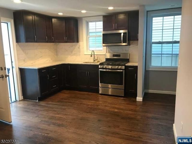 kitchen with decorative backsplash, a healthy amount of sunlight, dark wood-type flooring, and appliances with stainless steel finishes