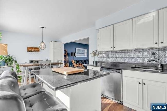 kitchen featuring white cabinets, tasteful backsplash, decorative light fixtures, dishwasher, and a breakfast bar area