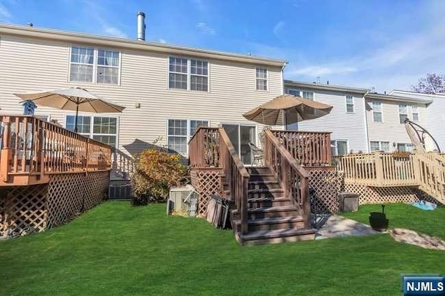 rear view of house with a lawn and a wooden deck