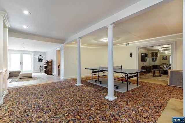 recreation room with carpet flooring, brick wall, and french doors