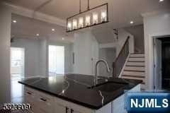 kitchen with pendant lighting, a kitchen island, white cabinetry, and sink